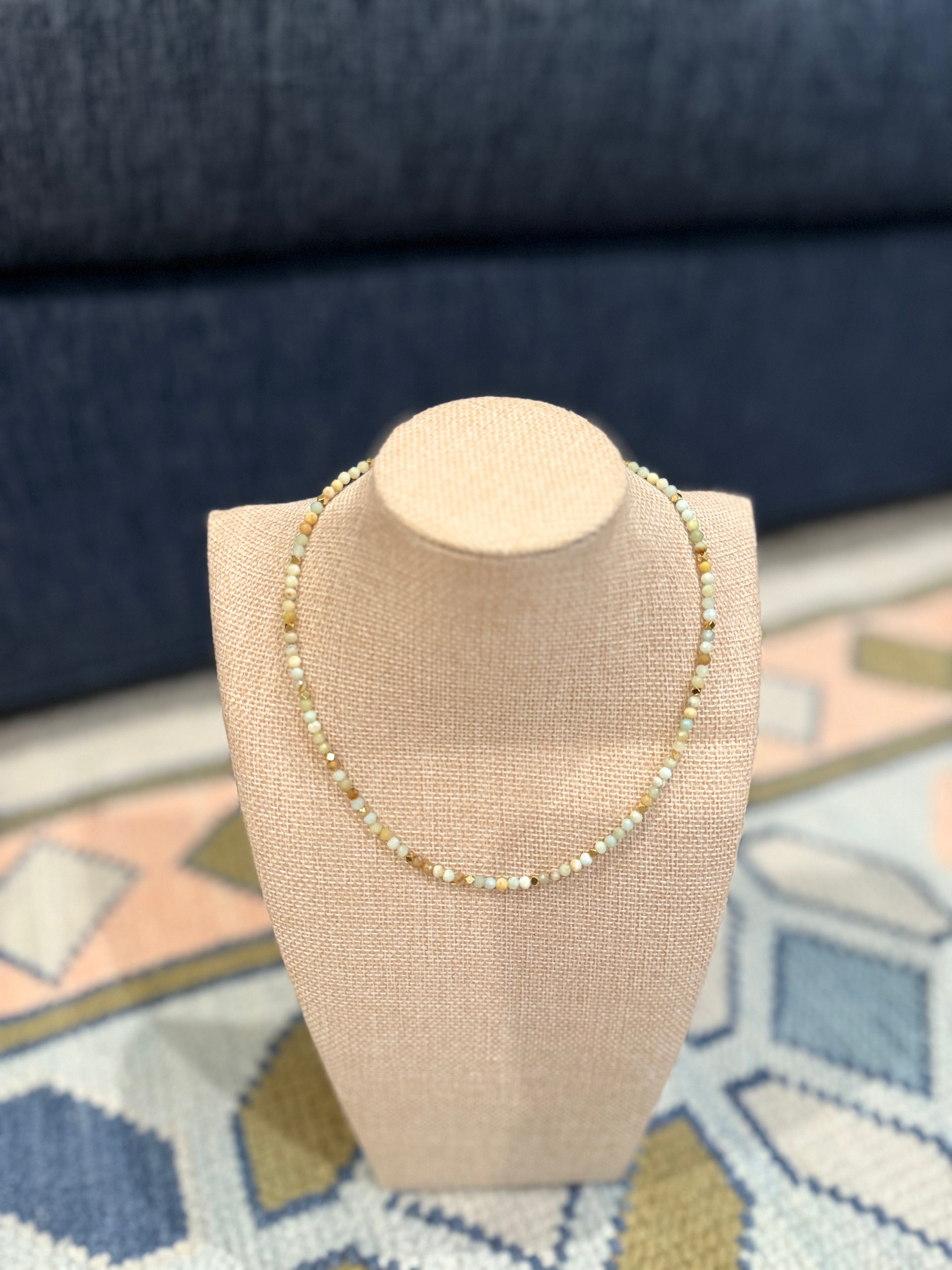 Necklace on a beige display stand with a blue and patterned background