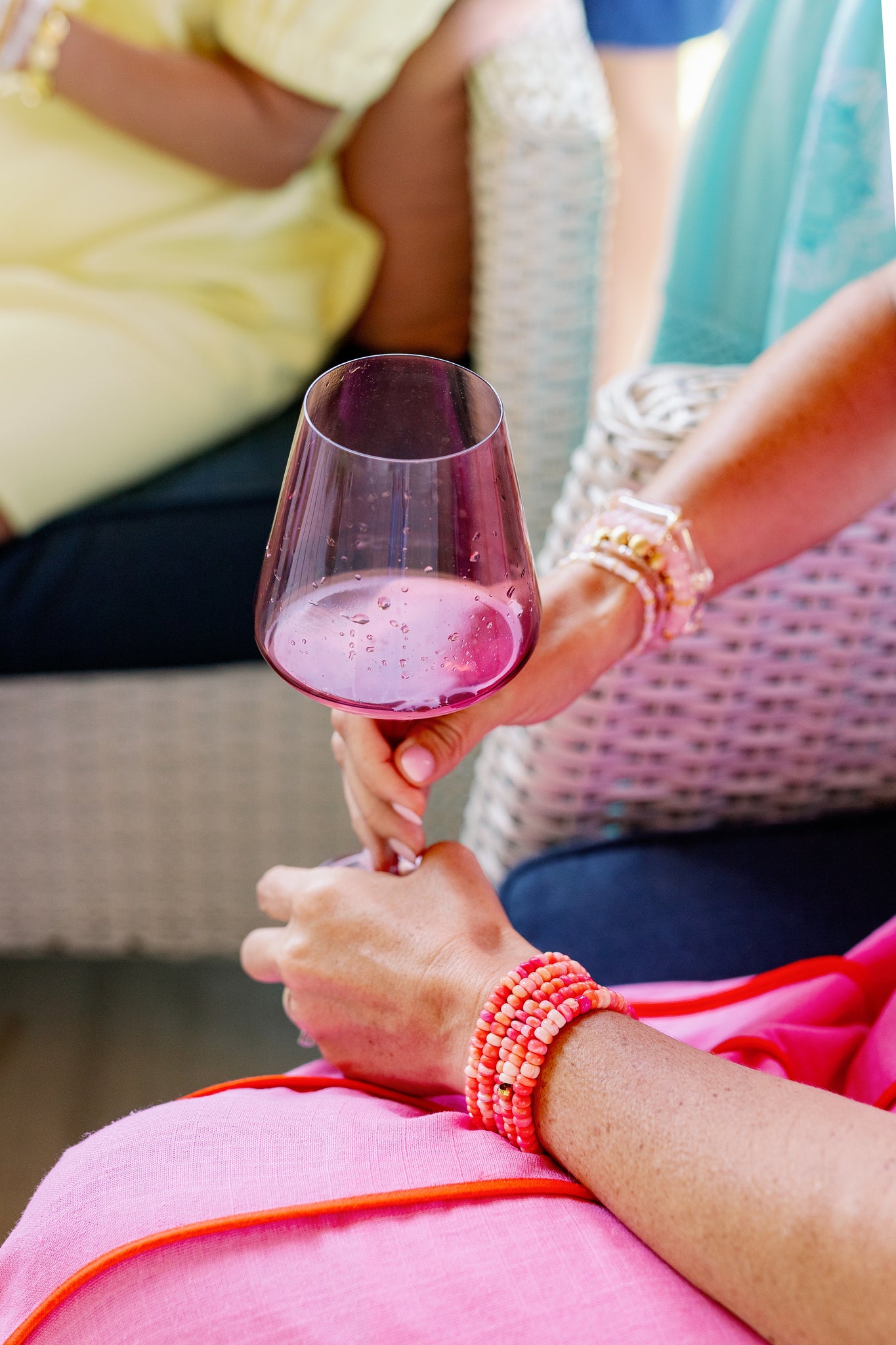 woman holding wine glass with coral pebble beaded bracelets on her wrist