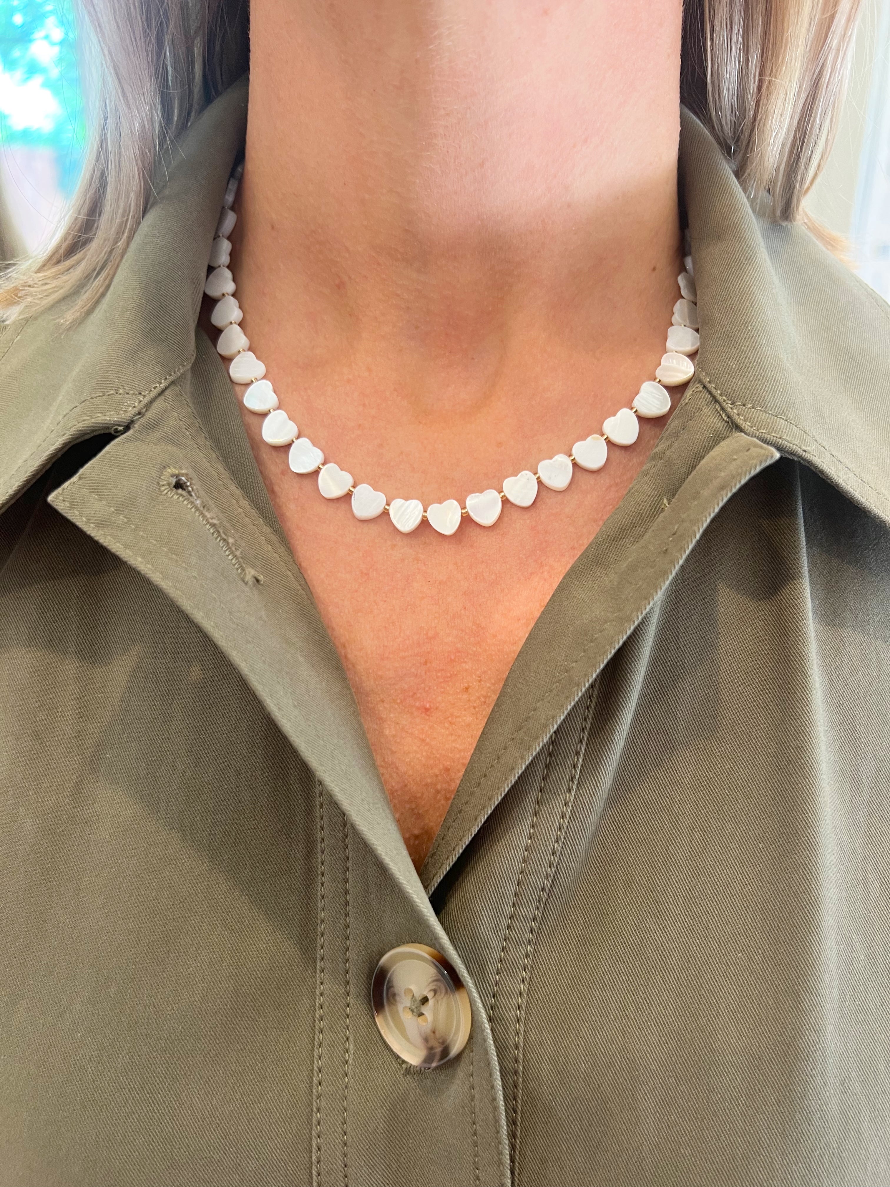 Person wearing a green jacket with a heart-shaped necklace